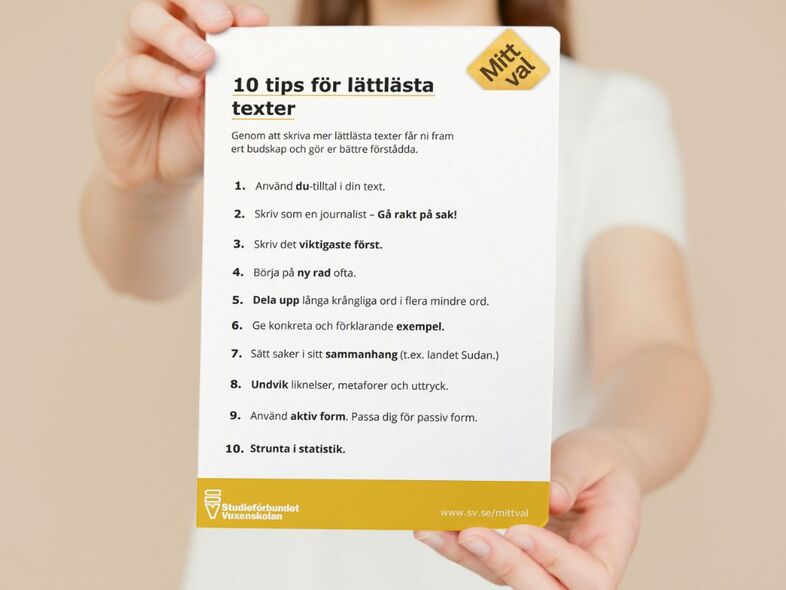 En person håller fram en lista med båda händerna på tips för lättlästa texter.