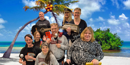 En grupp glada personer poserar framför en strandbakgrund med palmer och blå himmel.