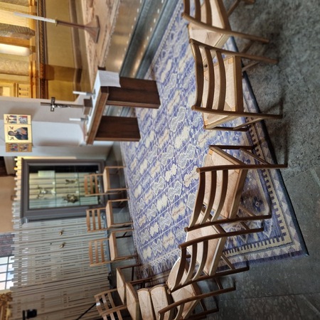 Stolar i en cirkel runt ett altare i ett kyrkorum med matta och religiösa symboler.