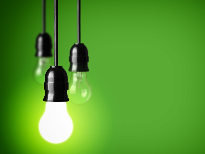 Tre hängande glödlampor mot en grön bakgrund, en av lamporna lyser starkt.