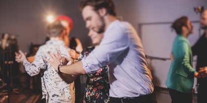 En grupp människor dansar tillsammans i ett rum med dämpad belysning.