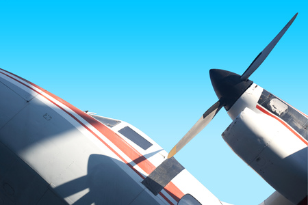 Närbild av ett propellerflygplans motor och vinge mot en klarblå himmel.