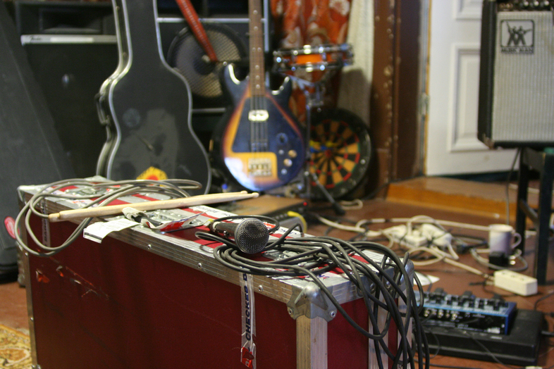 En replokal med gitarrer, högtalare, mikrofon och en massa sladdar.