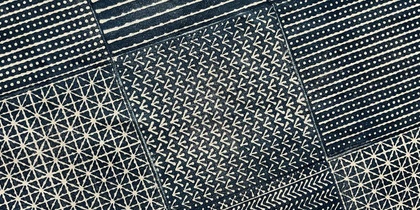 Ett mörkblått och vitt tyg indelat i rutor med olika handtryckta geometriska mönster i japanskinspirerad stil