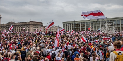 Stor folkmassa samlad på ett torg med många vit-röda flaggor under en demonstration.
