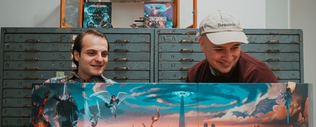 Två personer sitter vid ett bord med Dungeons & Dragons böcker, tärningar och spelledarskärm.