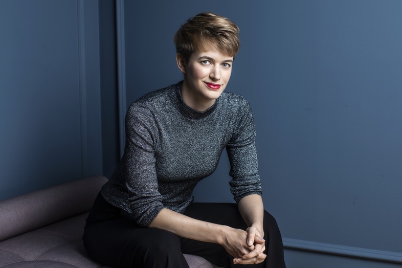 Person sitter på en bänk i ett rum med blå väggar och håller händerna i knät.