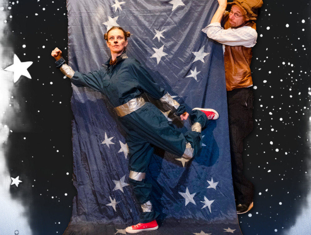 Två personer poserar framför ett blått tyg med vita stjärnor, en i overall och en i väst, mot en stjärnhimmelbakgrund.