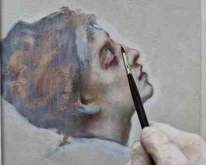 En hand målar ett realistiskt porträtt av en kvinna i profil med en pensel på en duk.