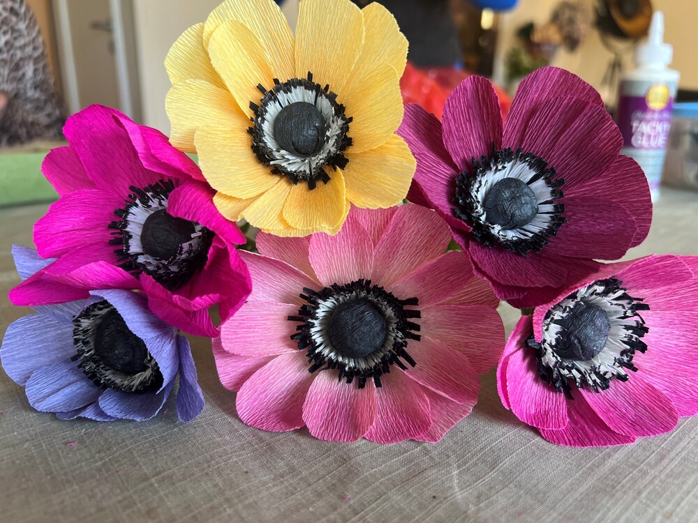 Färgglada blommor av crepepapper i olika färger ligger på ett bord.