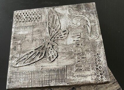 Dekorativt konstverk med fjäril, texten 'DREAM' och olika mönster i svartvitt.