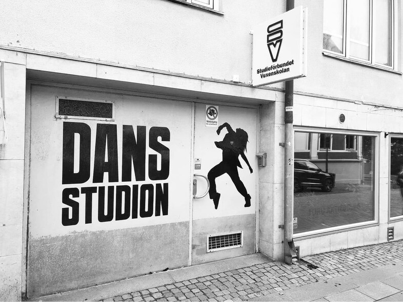 Ingång till en dansstudio med stor text 'DANS STUDION' och en siluett av en dansare på dörren.
