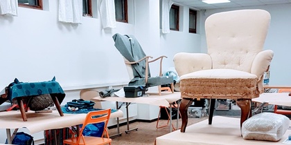 Ett klassrum med stolar och fåtöljer placerade ovanpå borden, inga människor syns.