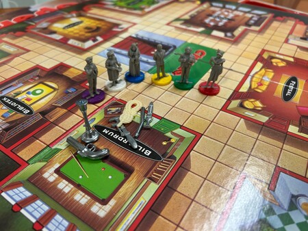 Brädspel Cluedo med spelpjäser och vapen på spelplanen, nära biljardrummet.