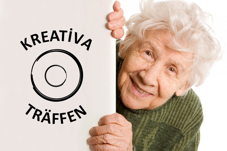 Leende äldre kvinna i grön tröja håller i en skylt med texten 'Kreativa träffen' och en cirkelgrafik.