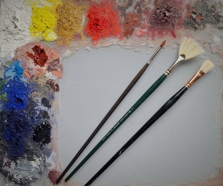 En konstnärspalett med färgklickar i olika färger och tre penslar ovanpå.