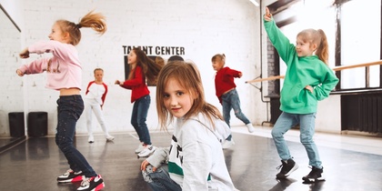 Barn dansar i en ljus dansstudio med stora fönster och spegelvägg.