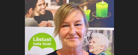 Kvinna med blont hår står framför en affisch med texten 'Läslust hela livet' och bilder på människor och gröna ljus.