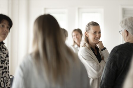 Människor står i ett ljust och pratar med varandra i grupper.