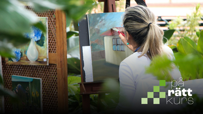 Kvinna målar en tavla utomhus omgiven av växter och andra konstverk.