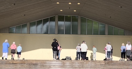 En grupp människor står utspridda på en utomhusscen med trappsteg framför.