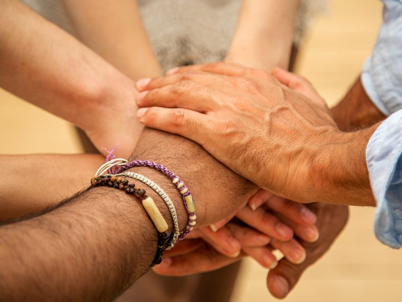Flera händer lagda ovanpå varandra i en gest av samarbete och gemenskap.