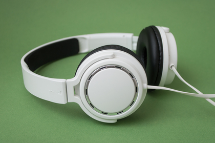 Vita hörlurar med sladd ligger på en grön bakgrund.