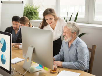 Fyra personer arbetar tillsammans vid datorer i ett ljust kontorslandskap.