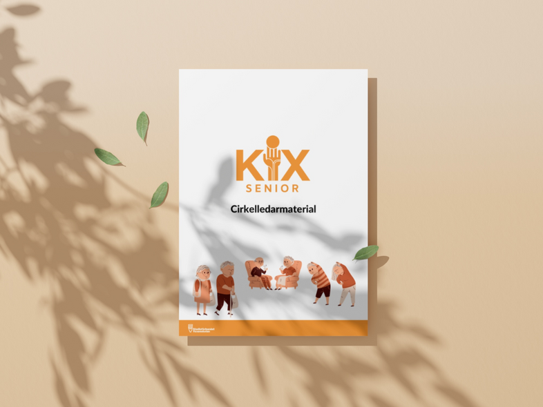 Ett häfte med titeln 'Kix Senior Cirkelledarmaterial' ligger på ett beige underlag med skuggor och gröna blad.