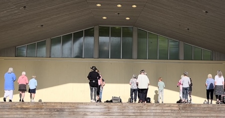 En grupp människor står utspridda på en utomhusscen med trappsteg framför.