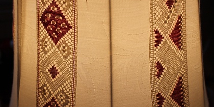 Närbild av en lampskärm med broderade och virkade mönster i beige och vinrött.