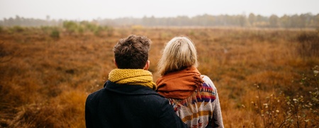 Två personer står med armarna om varandra och tittar ut över ett höstlandskap.