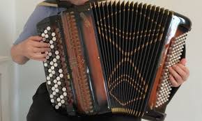 En person spelar på ett dragspel med många knappar och bälg.