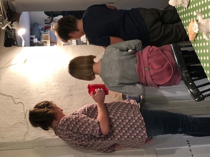 Tre personer står vid ett bord i ett kök och förbereder något tillsammans.