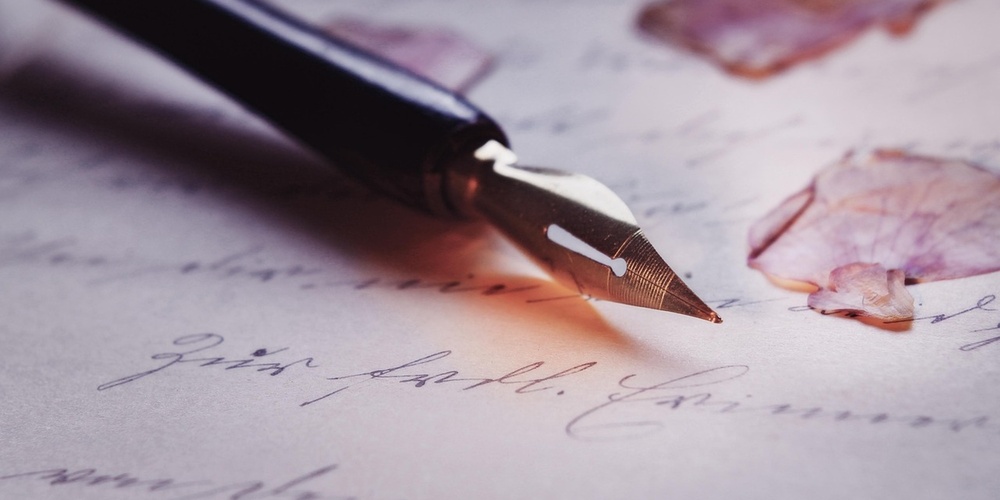 En närbild av en reservoarpenna på ett handskrivet brev med torkade blomblad.