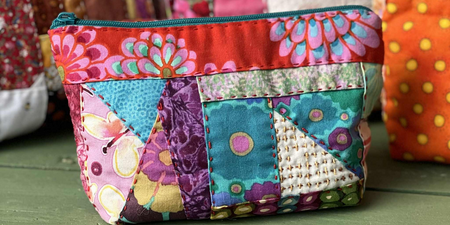 Väska i lapptäcksteknik framför flera väskor i samma stil.