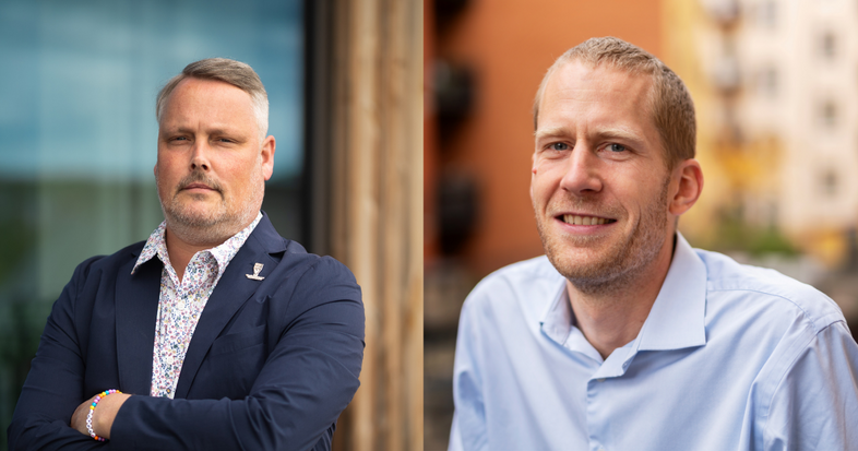 Två män poserar utomhus, en i kavaj med armarna i kors och en i ljusblå skjorta som ler.