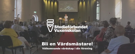 Föreläsning i en stor sal med publik, scen och projektor. Text om Studieförbundet Vuxenskolan syns.