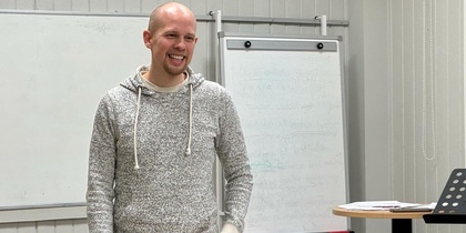 En person står i ett klassrum framför en whiteboard och ett blädderblock.