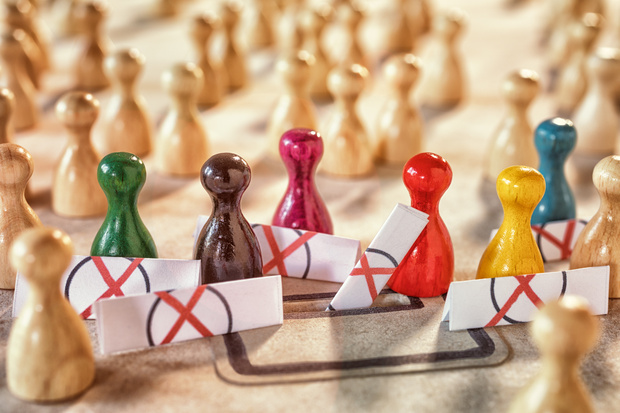 Färgade spelpjäser står i en grupp omgivna av barriärer med röda kryss, fler pjäser i bakgrunden.