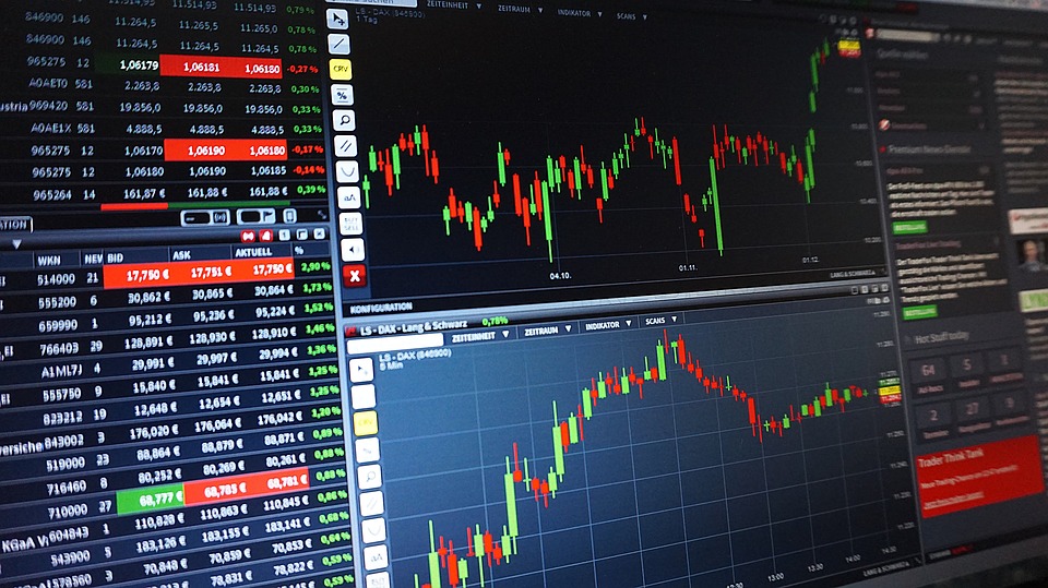 Datorskärm med aktiekurser, grafer och finansiell information i olika färger.