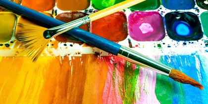 Närbild av en färgglad akvarellpalett med två penslar och målade färgfält.