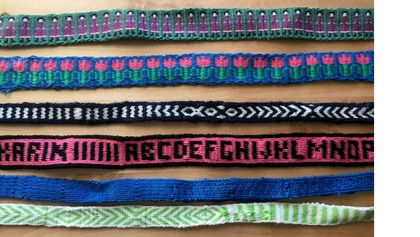 Sex färgglada band med olika mönster, inklusive figurer, blommor, bokstäver och geometriska former, ligger på ett bord.