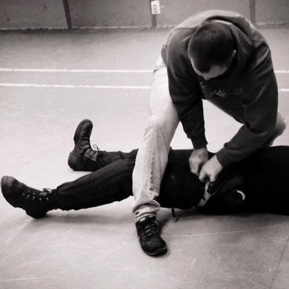 Två personer brottas på golvet, en håller fast den andra i ett grepp.