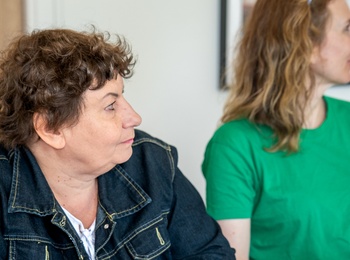 Två kvinnor sitter vid ett bord och antecknar under ett möte eller en workshop.