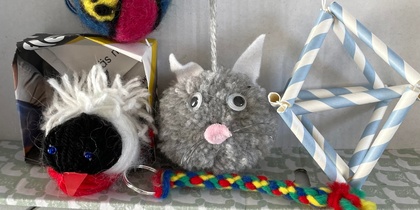 Flera färgglada handgjorda prydnader, inklusive en boll med kattansikte, en fågel och en geometrisk figur av sugrör.