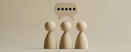 Tre träfigurer står bredvid varandra med en pratbubbla ovanför dem mot beige bakgrund.