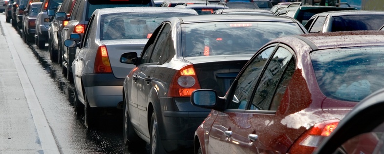 Bilkö på en våt väg, flera bilar står stilla i tät trafik.