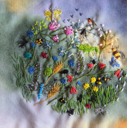 Broderi av en blomsteräng med fjärilar, bin och blommor i olika färger på tyg.