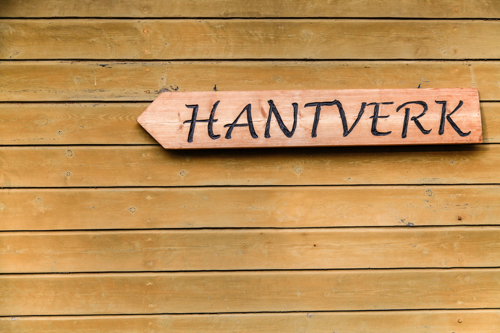Träskylt med texten 'HANTVERK' på en trävägg.